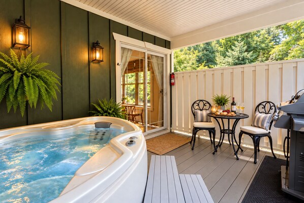A hot tub on a wooden deck with outdoor seating and a grill.