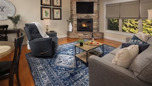 A living room with a stone fireplace, a blue patterned rug, and a comfortable seating area.