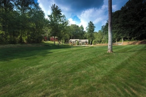 A well-maintained grassy area with a house in the background surrounded by trees.
