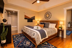 Une chambre à coucher avec un lit en bois, un globe terrestre posé sur un bureau, un tapis à motifs et un miroir fixé au mur.