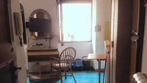 A room with a desk, chair, and a window with natural light. - THE PANATICS Studio apartment (Gaeta, Italia)