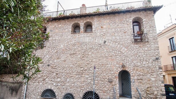 A stone building with a balcony, arched windows, and a small door. - THE PANATICS Studio apartment (Gaeta, Italia)
