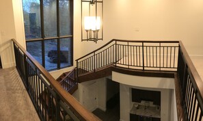 Stairs connect two levels in this spacious interior, featuring a fireplace and large window with a view.