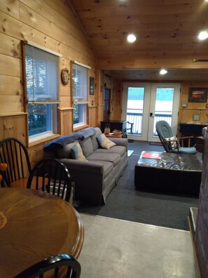 L’intérieur chaleureux d’un chalet avec un canapé, des fauteuils, une table à manger et une cheminée.