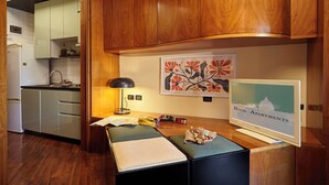 Eine kompakte Küche mit Holzausstattung, einem Essbereich mit Tisch, einer Lampe und einem gerahmten Bild an der Wand.