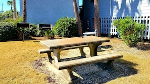 Enjoy a meal al fresco at this outdoor picnic table, surrounded by lush greenery and a charming picket fence.