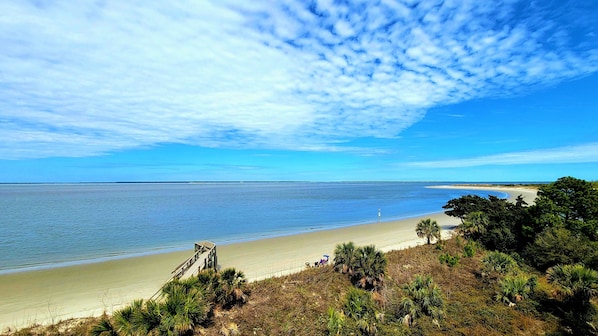Enjoy a serene beach experience with a tranquil view of the ocean and lush surroundings.