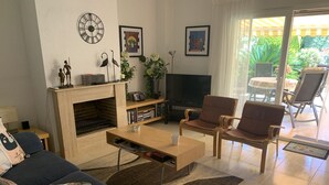 Un salon comprenant un canapé, une table basse, un téléviseur, une cheminée et deux fauteuils.