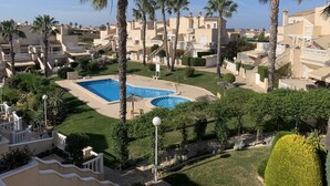 Un complexe hôtelier doté d’une piscine centrale, entourée de palmiers et de pelouses bien entretenues.