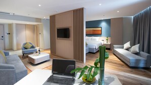 A modern hotel room with a flat-screen TV, a laptop on a white table, a sofa, a bed, and a large window. - Halong Pearl Hotel (Bai Chay)