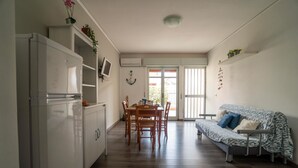 A compact living space with a kitchenette, dining area, and a sofa. - Anchor Apartment (Marina di Ragusa)