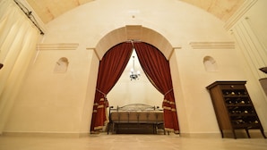 Quarto com cama sob teto em arco, um candelabro e um espaço para vinhos.