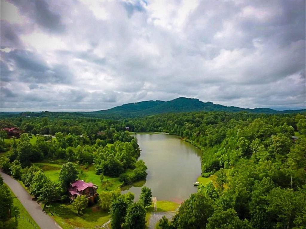 Un lago circondato da una fitta foresta e una catena montuosa sullo sfondo.