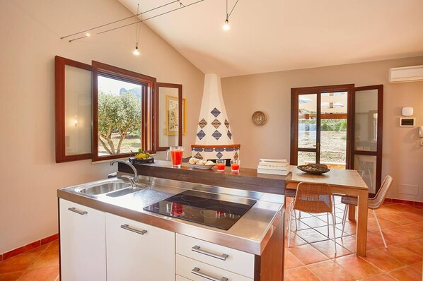 A kitchen with a central island, a dining table, and a view of the outdoors.