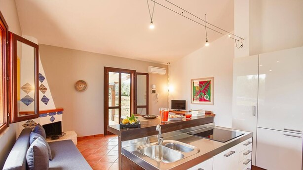 Una cocina moderna con una isla integrada, electrodomésticos de acero inoxidable y una zona de estar con sofá y cojines.