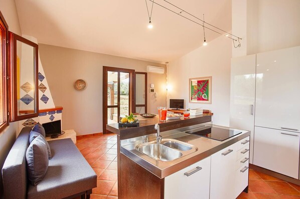 A modern kitchen with a built-in island, stainless steel appliances, and a seating area with a sofa and cushions.