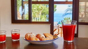 Una mesa con croissants, dos vasos de bebida roja y una jarras de jugo rojo.