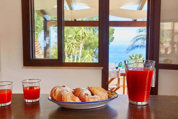 A table with croissants, two glasses of red beverage, and a pitcher of red juice.
