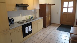 Una cocina con armarios color beige, una estufa negra y una puerta de madera.