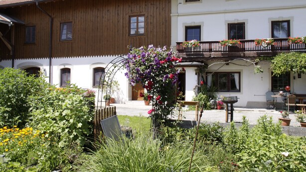 Un edificio tradicional con fachada de madera y un balcón lleno de flores.