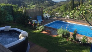 A backyard with a swimming pool, lounge chairs, and a hot tub.