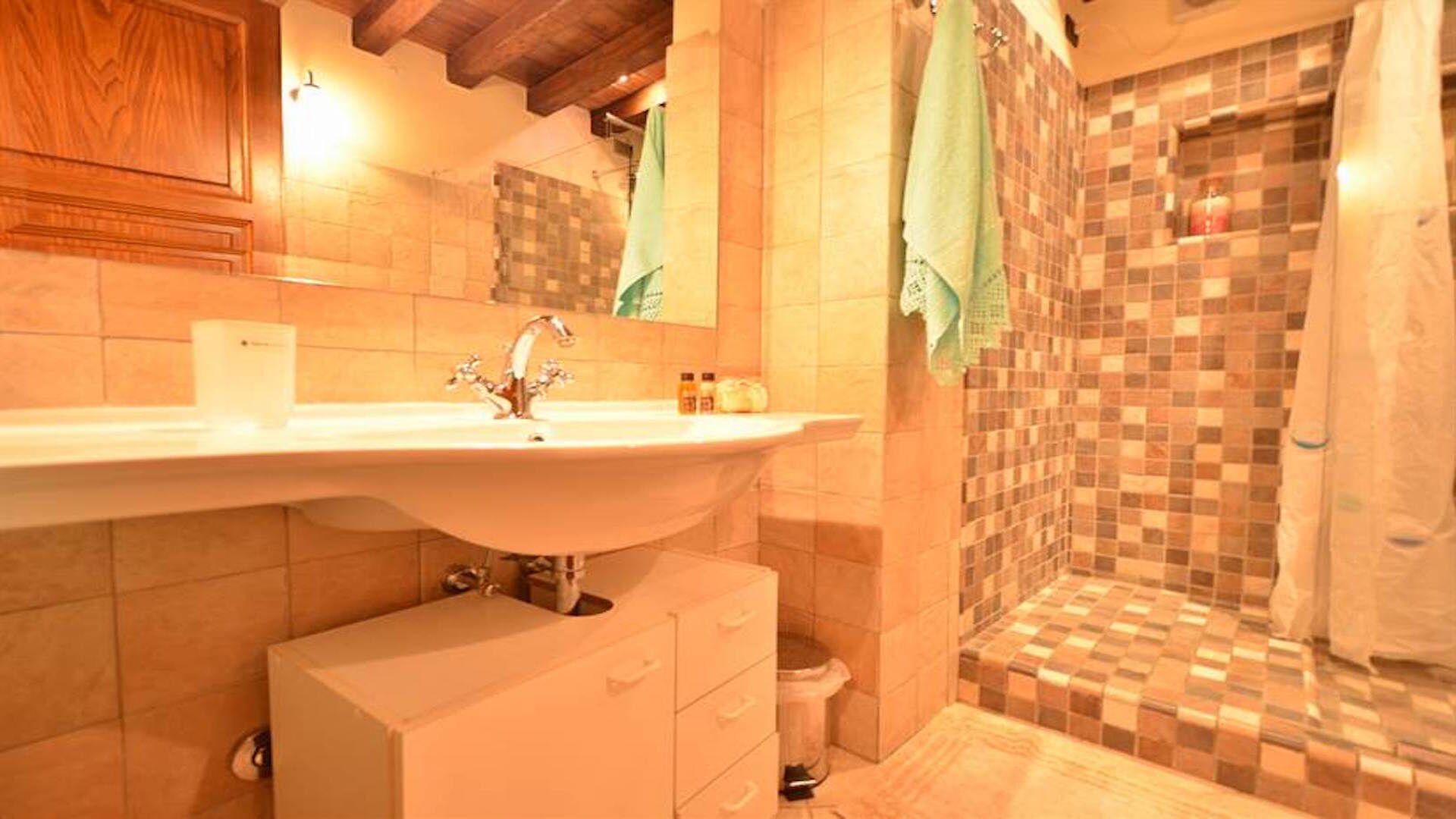 Ein Badezimmer mit einem großen Waschbecken, einem Spiegel und einer Duschkabine mit Schachbrettfliesen.