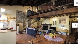 A rustic interior with a kitchen, dining area, and a stone fireplace.