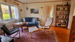 A cozy living room with a sofa, a coffee table, a bookshelf, and a chair.