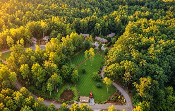 An aerial view of a residential area with houses surrounded by dense greenery and a well-maintained lawn. - Super Clean Cottage with Private Hot Tub and Fireplace (Asheville)