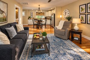 Un salon comprenant un canapé, un fauteuil, une table basse et un coin repas agrémenté d’un lustre.