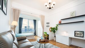 A modern living room with a leather sofa, a round coffee table, a city view through large windows, and a chandelier. - An Corner The Manor The Art - Saigon Central (Ho Chi Minh City)