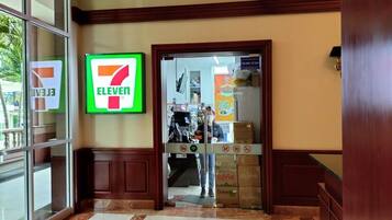 A 7-Eleven convenience store entrance with a glass door, a tiled floor, and a wooden interior.