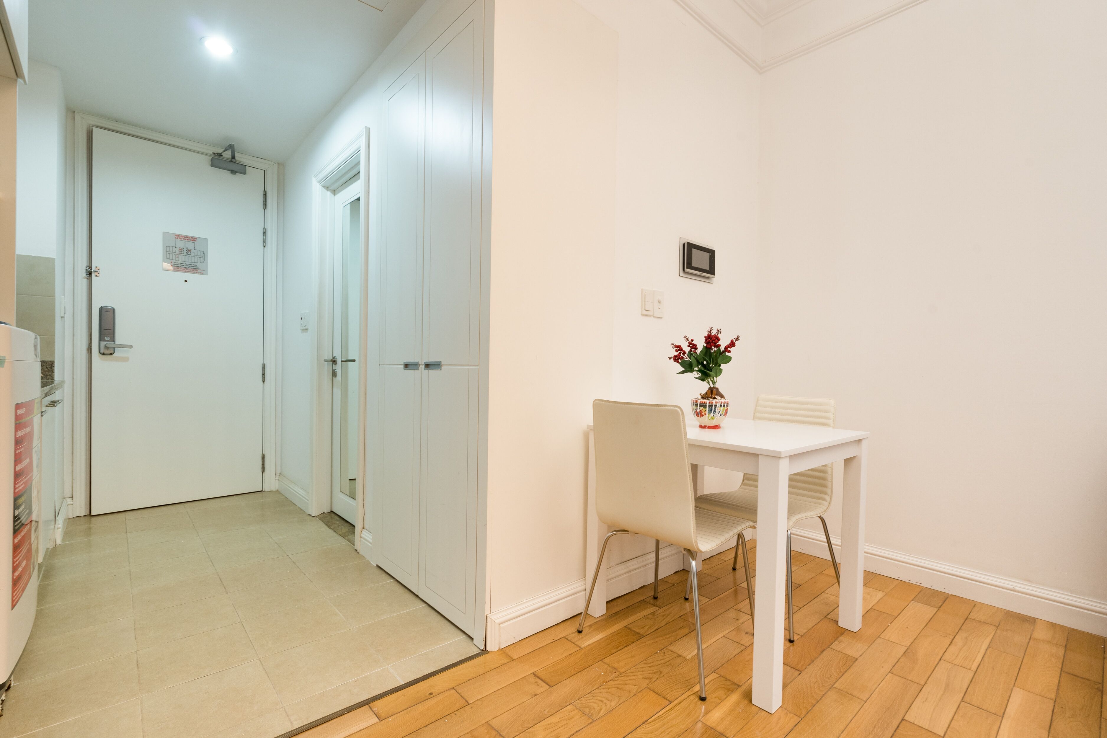 Un pasillo con una puerta blanca, una pequeña mesa con una silla y una planta en maceta.