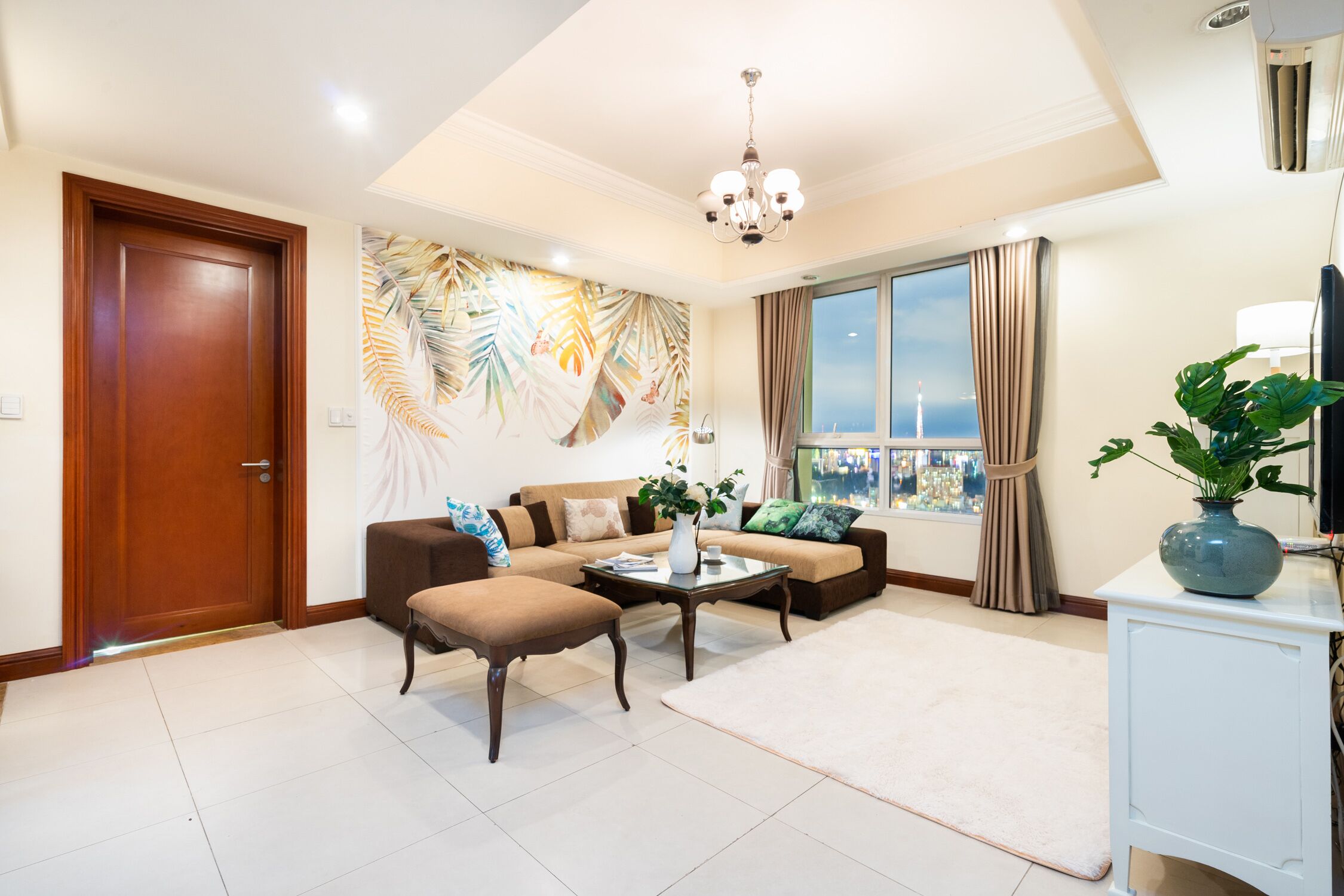 A spacious living room with a sofa set, a coffee table, and a large window with a view.