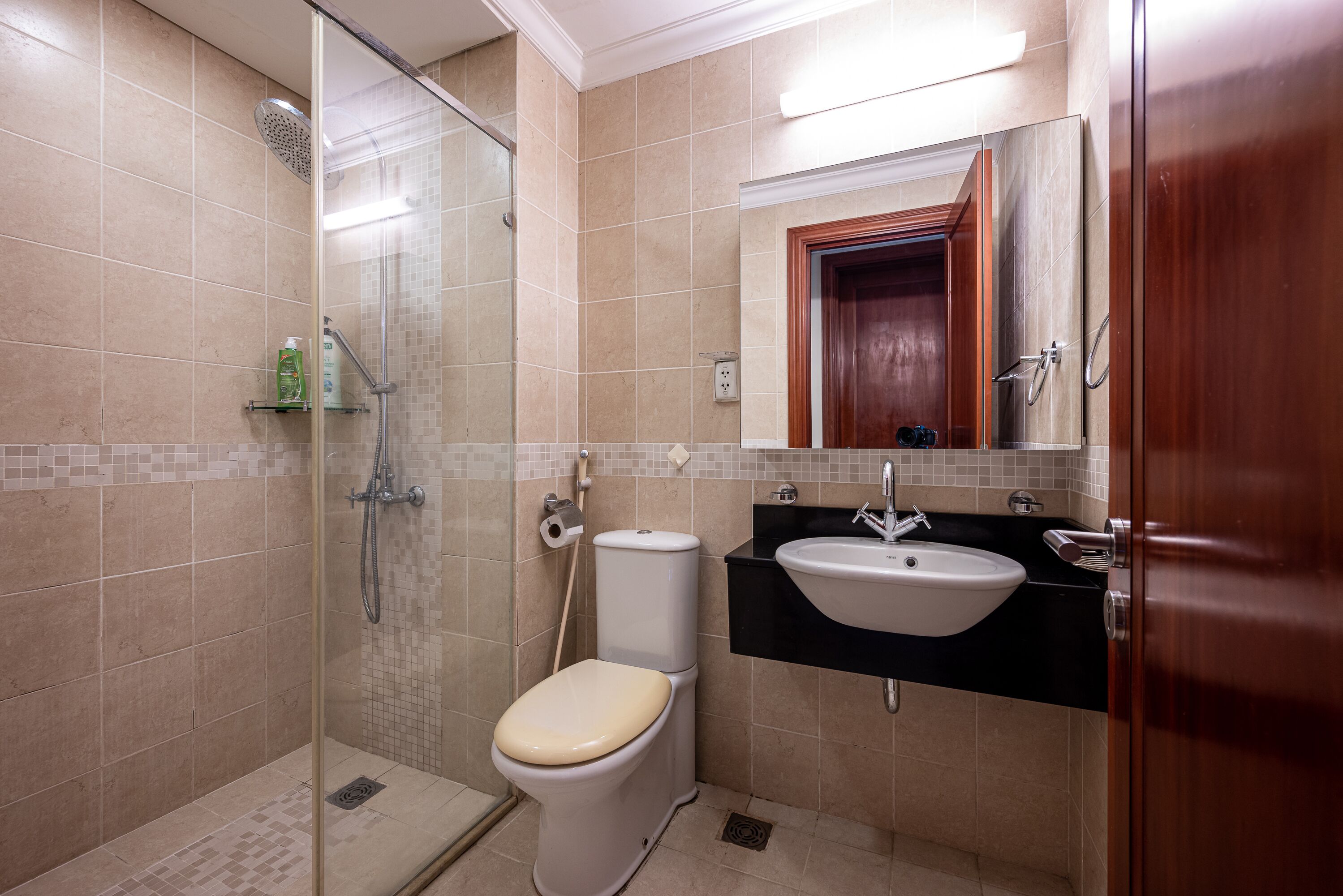Ein modernes Badezimmer mit einer Duschkabine, einer Toilette, einem Waschbecken und einem Spiegel über dem Waschbecken.