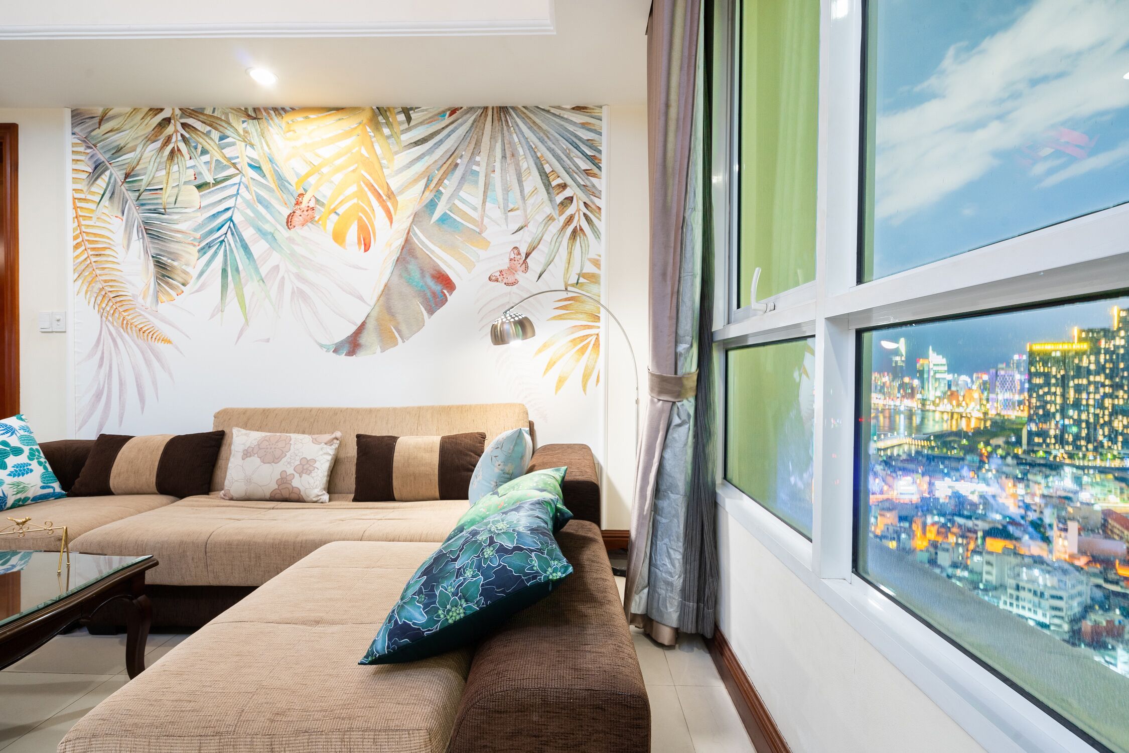 A living room with a sofa set, a coffee table, and a large window with a city view.
