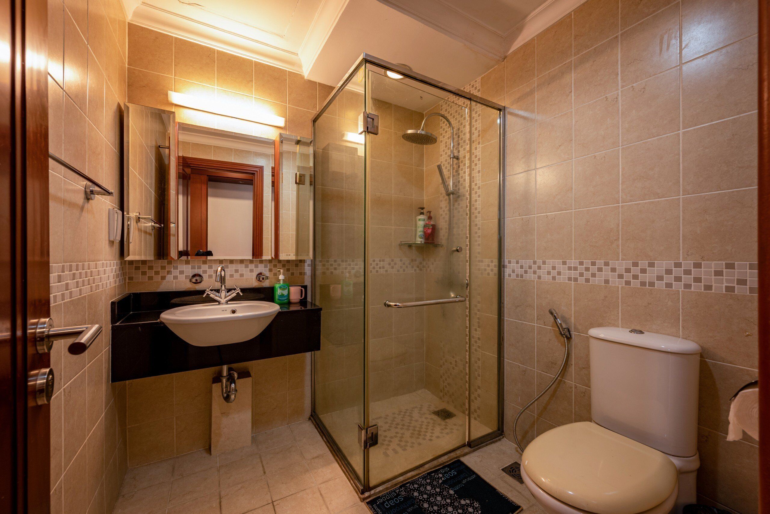 A bathroom with a glass-enclosed shower, a sink, and a toilet.