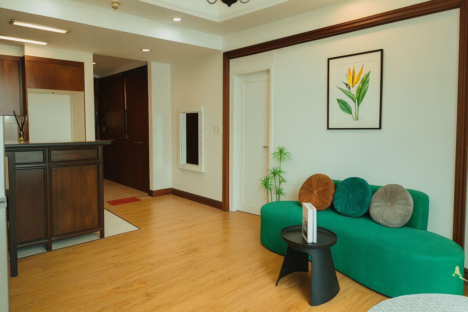 Un salon moderne avec un canapé vert, une petite table d’appoint noire et une estampe botanique encadrée accrochée au mur.