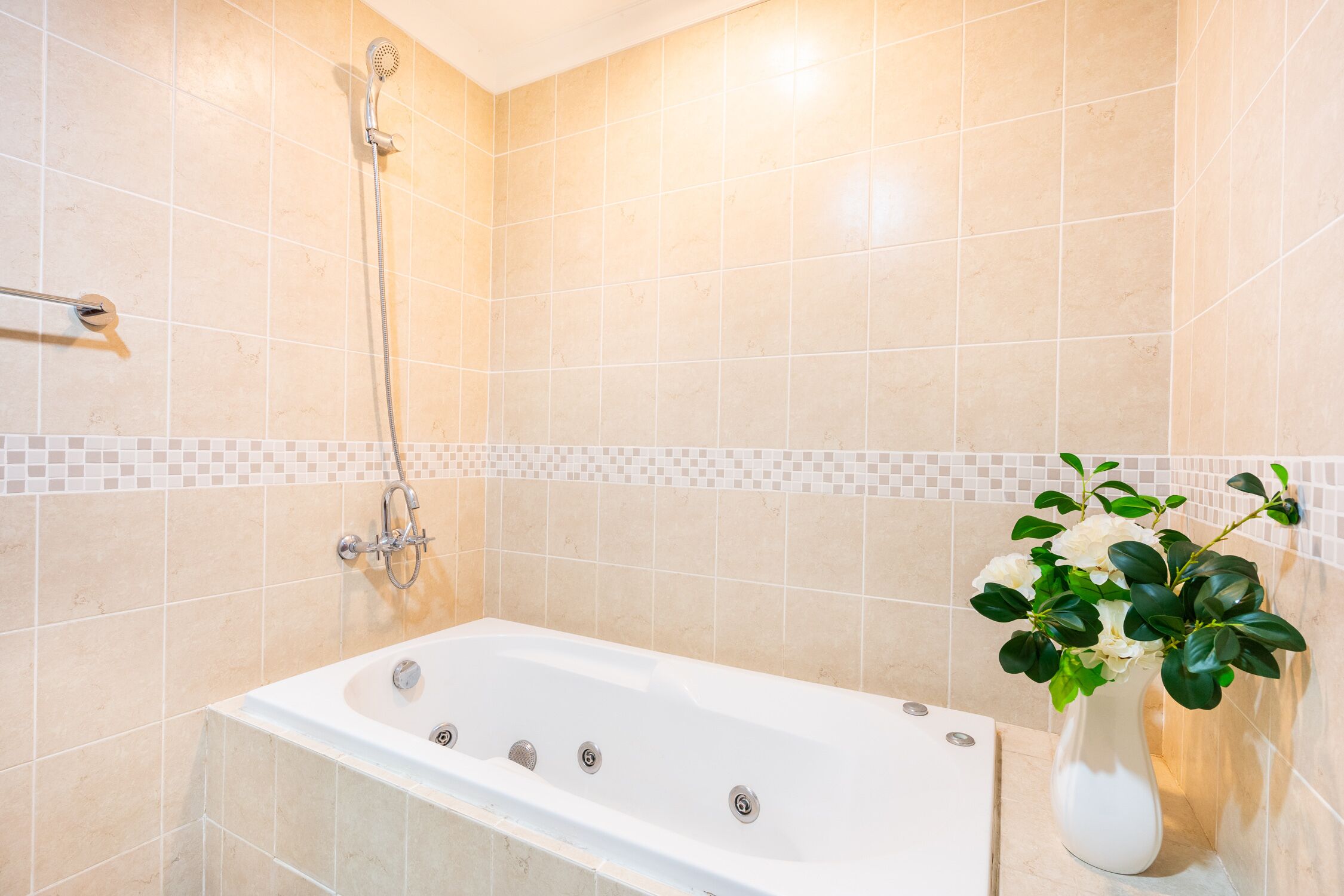 A modern bathroom with a bathtub, a shower, and a tiled wall.