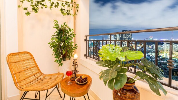 A balcony with wicker furniture, a candle, and a potted plant. - An Corner The Manor The Art - Saigon Central (Ho Chi Minh City)