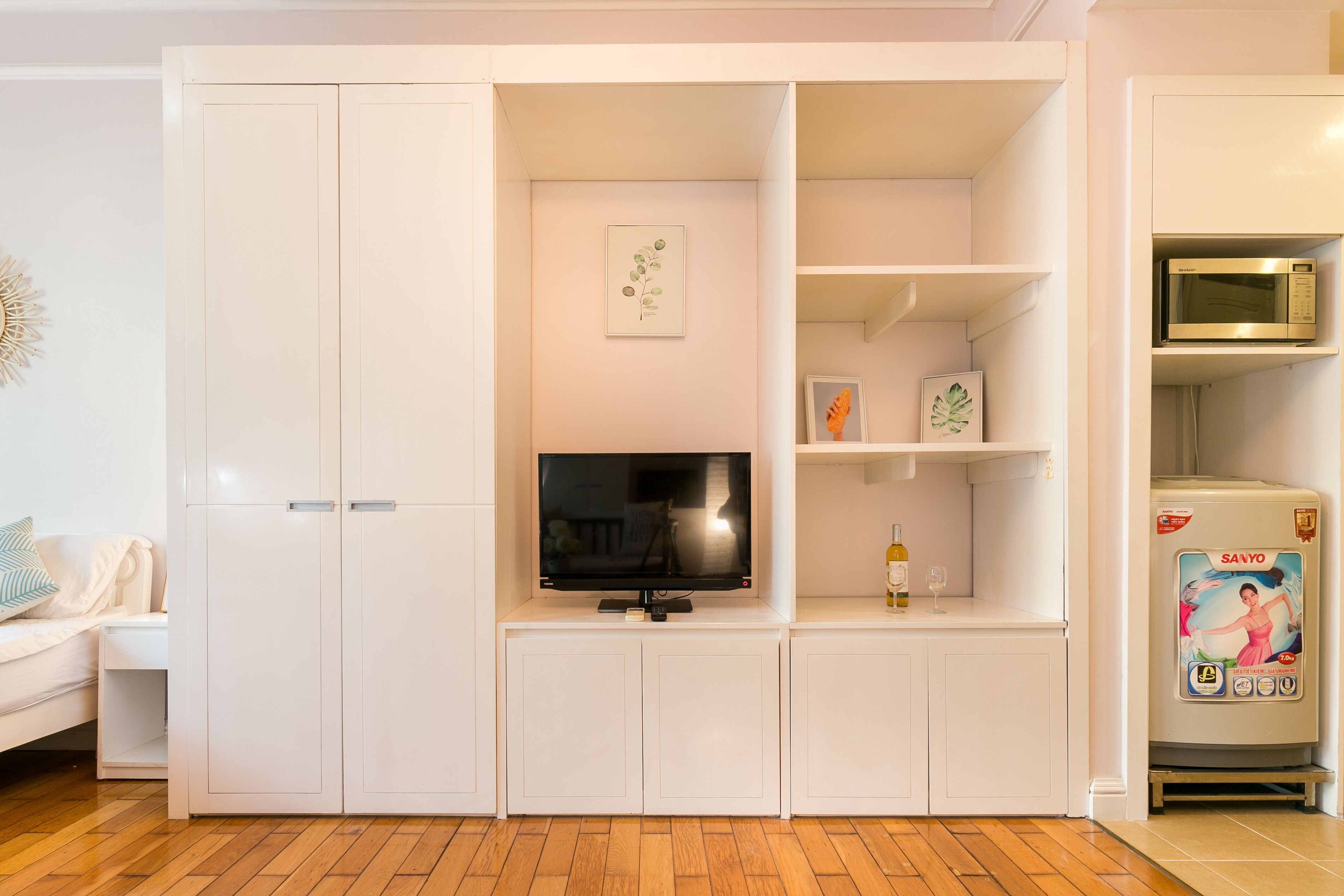 A living room with a TV, white cabinets, and a microwave.