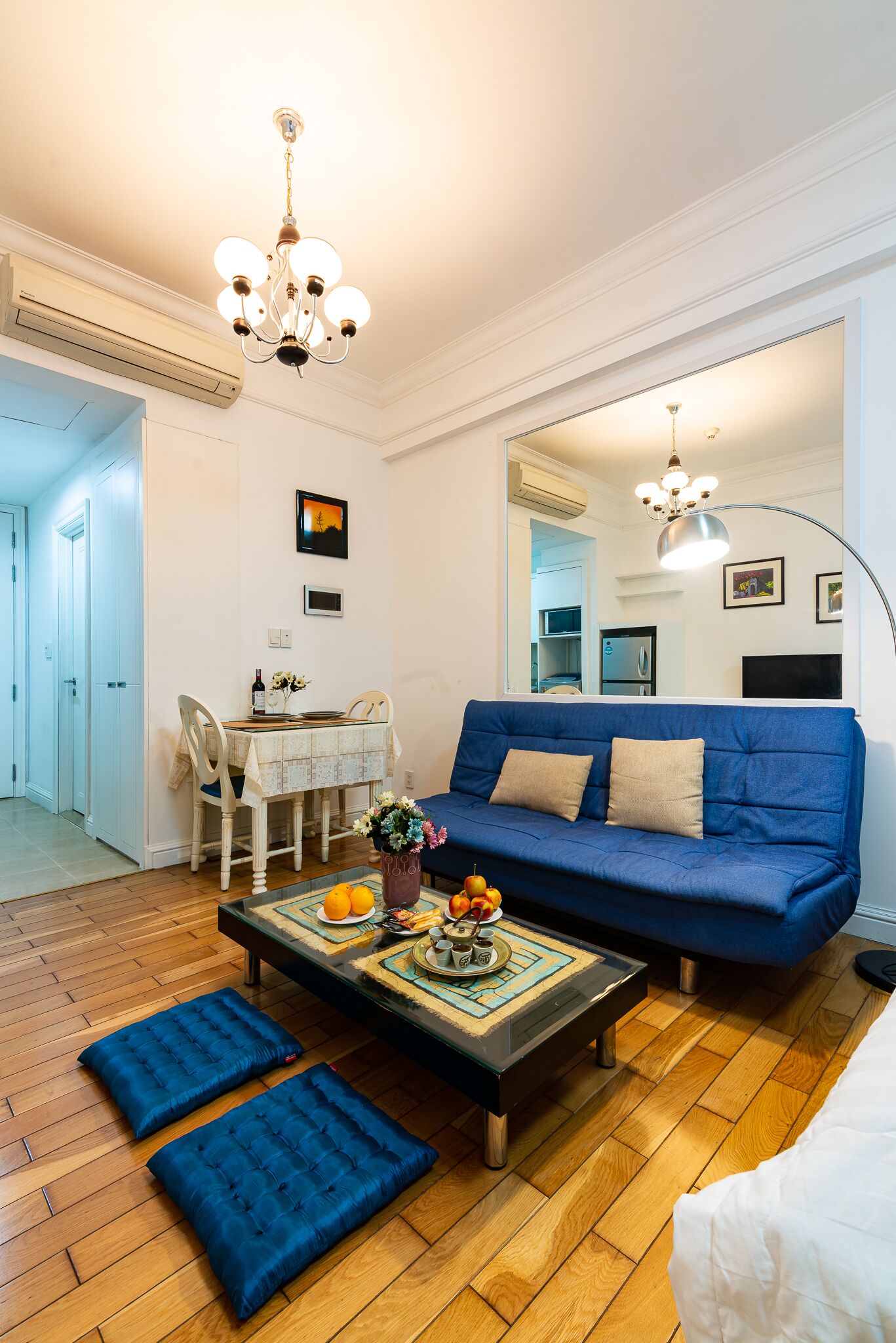 Ein Wohnzimmer mit einem blauen Sofa, einem Couchtisch mit Früchten und einer Kronleuchter.