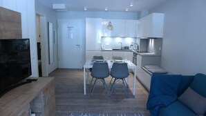 Un apartamento moderno con comedor, kitchenette y sala de estar con un sofá azul.
