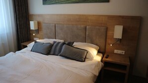 Una habitación de hotel con una cama grande, dos mesitas de noche y un cuadro en la pared.