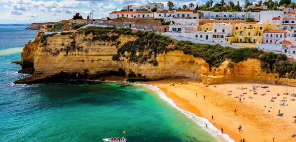 A coastal town with a cliff, beach, and colorful buildings.