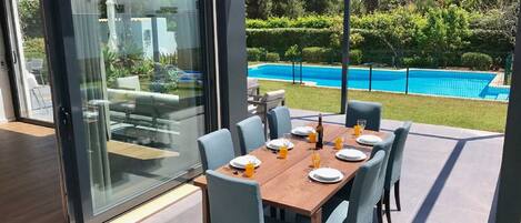 A dining area with a table set for six, overlooking a swimming pool.