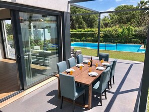 A dining area with a table set for six, overlooking a swimming pool.