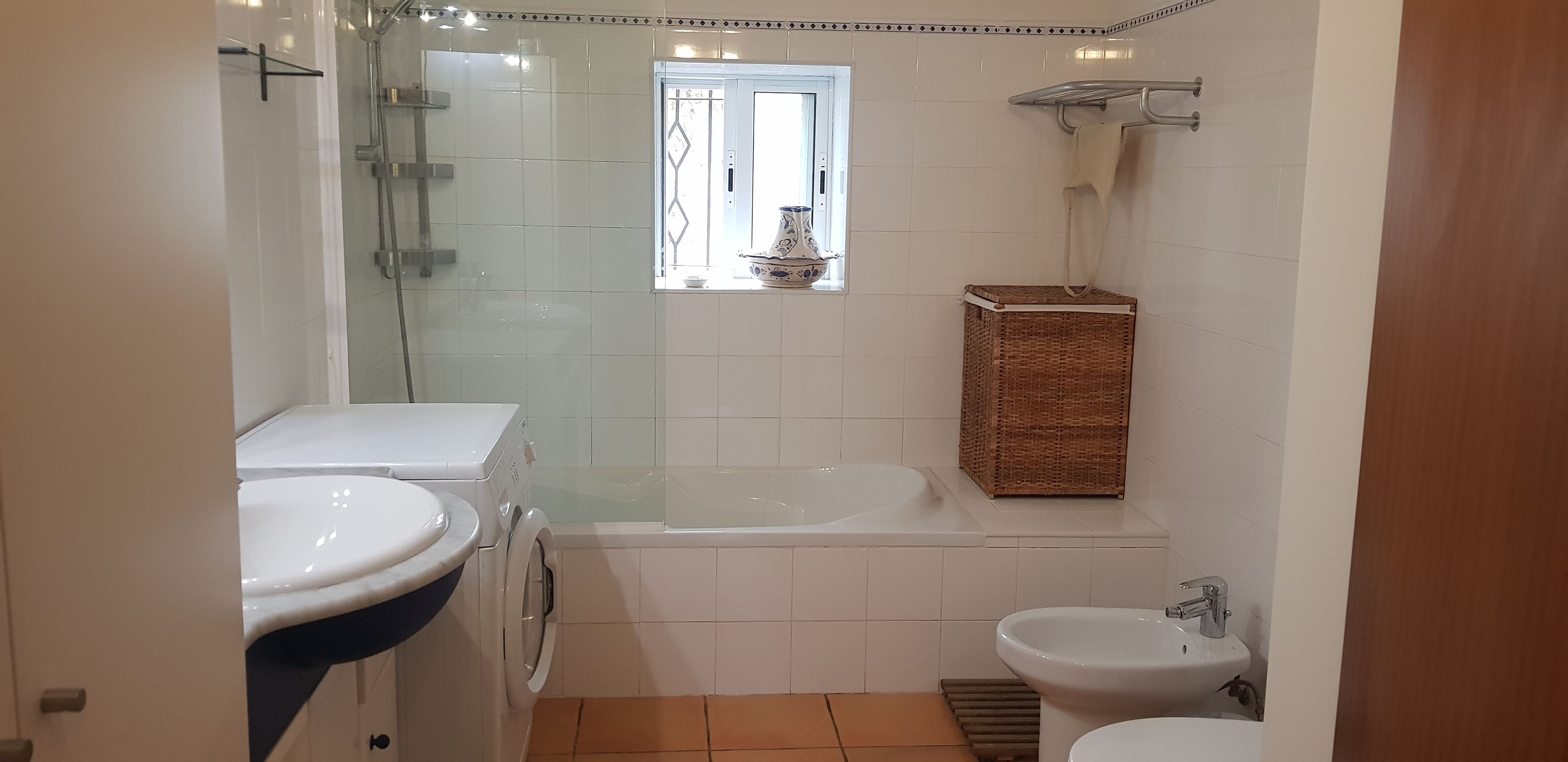 A bathroom with a glass-enclosed shower, a bathtub, a sink, and a bidet.