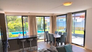 A modern kitchen with a dining area, a sofa, and large windows overlooking a pool. - Luxury detached villa with tropical garden and large private pool. Fully walled (Carvoeiro)
