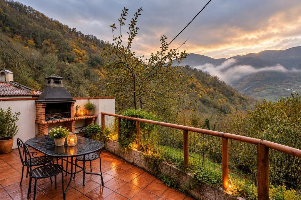 Eine Terrasse mit Grill aus Ziegelsteinen, Sitzgelegenheiten im Freien und Blick auf eine gebirgige Landschaft.